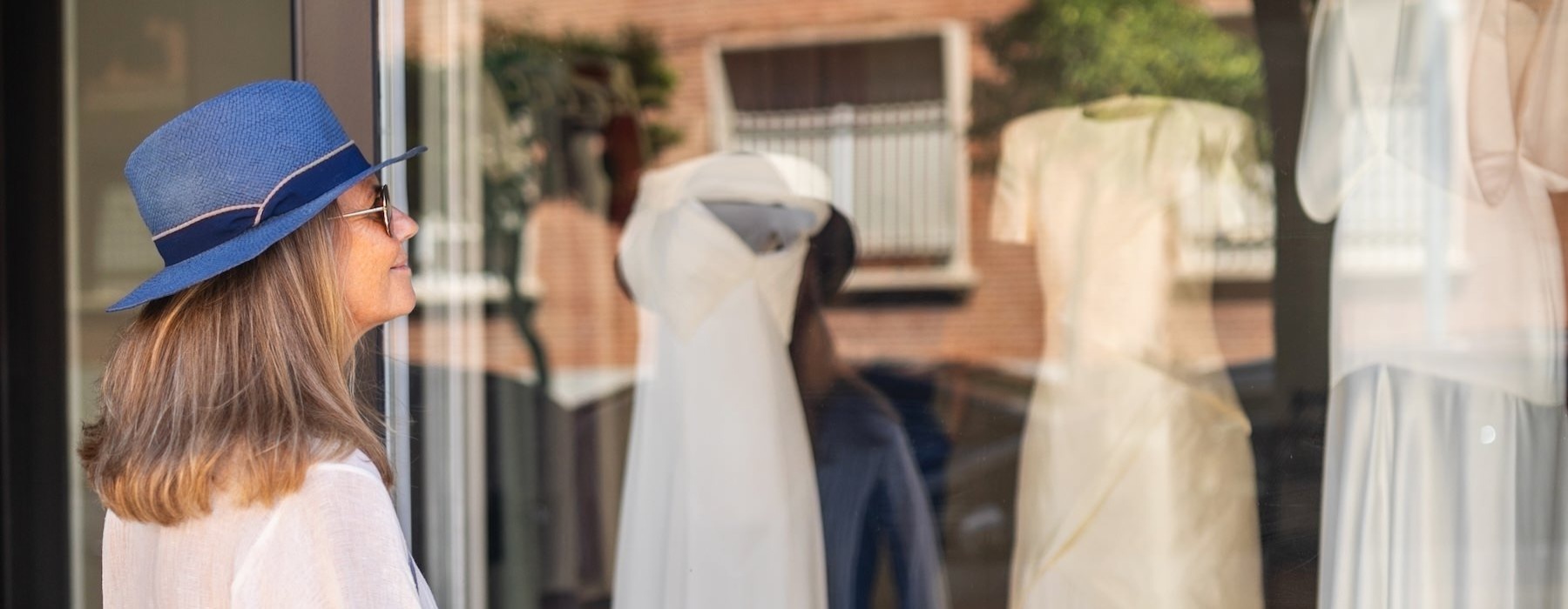 a woman looking at dresses through a window