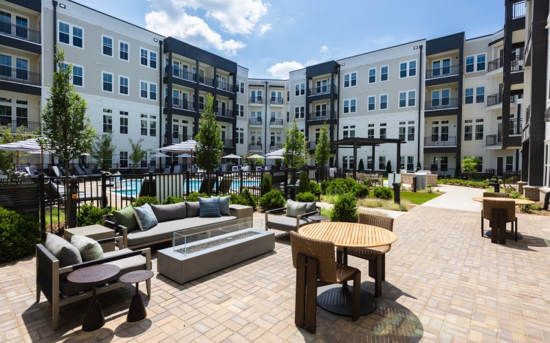 a poolside courtyard are with a couch, tables and chairs
